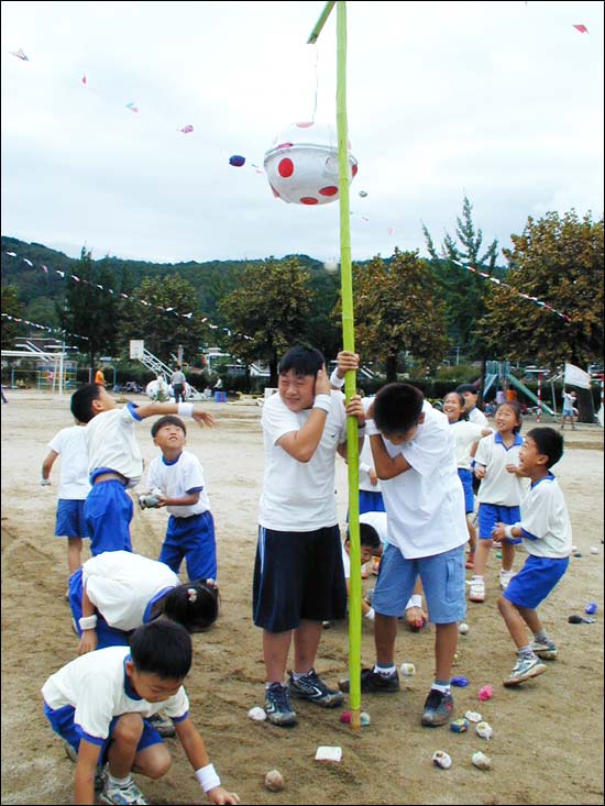 "던져 던져" 1, 2학년 41명의 학생들이 콩주머니를 던져 사탕바구니를 터트리려 하고 있다. 기둥을 잡고 있는 학생들은 고역스러운 듯. 